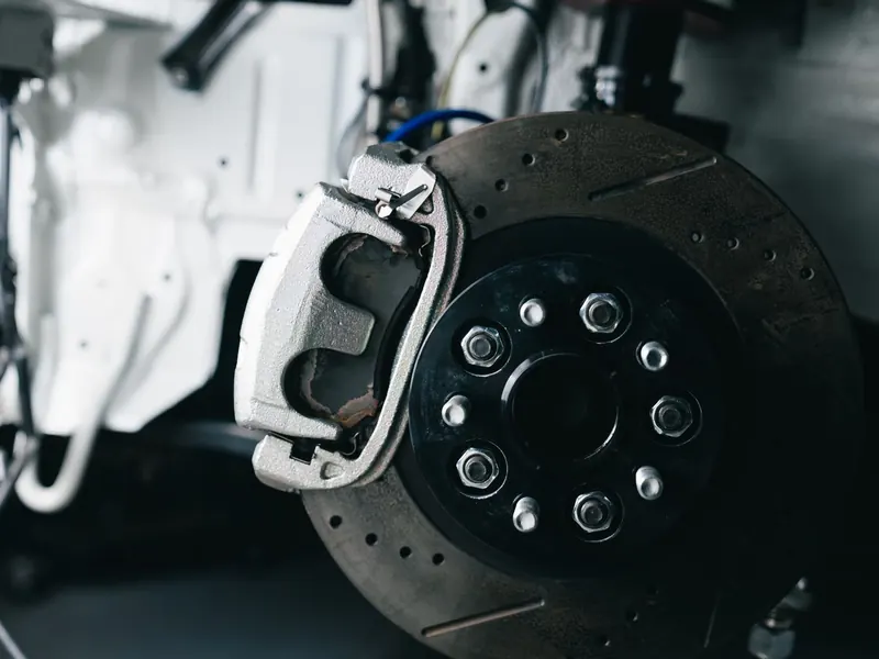 Close-up of a new brake disc and caliper fitted to a car hub in a workshop