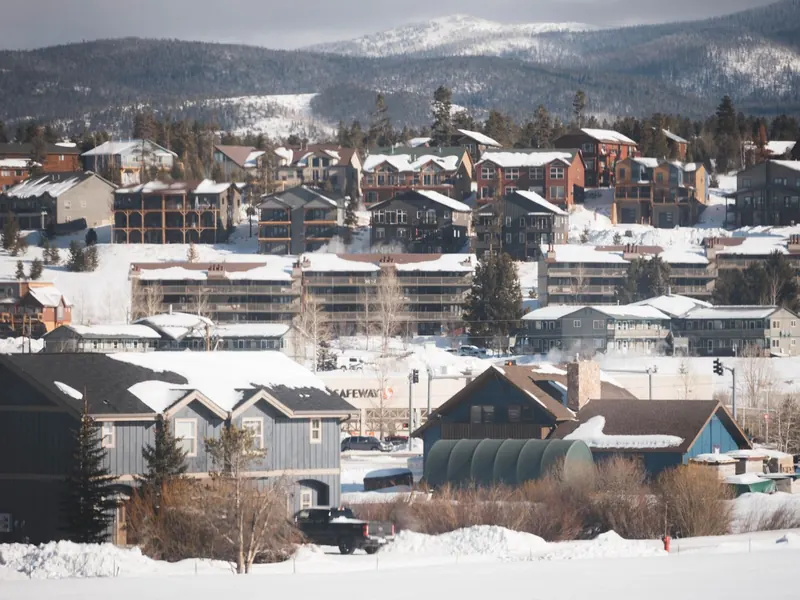 Snow-covered hillside neighbourhood with houses and mountains in the background