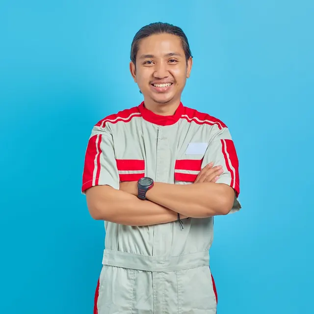 Smiling man in a work uniform with arms crossed against a blue background