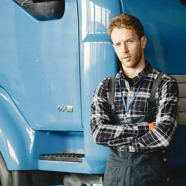 Technician in plaid shirt and overalls standing in a workshop