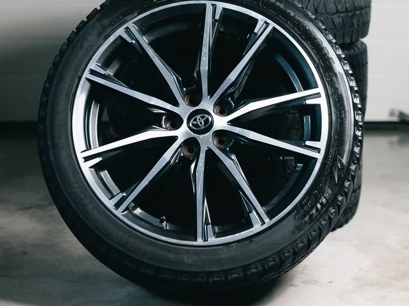 Two new tyres on alloy wheels stacked against a white workshop wall